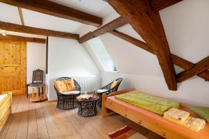 a attic room with a bed and chairs at Ferienwohnungen 'am Waldrand' in Bad Gottleuba
