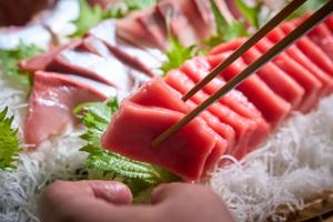 a person holding a piece of watermelon on a plate of food at Ooedo Onsen Monogatari Kaike in Yonago