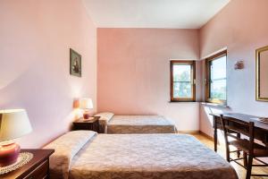 two beds in a room with two windows at Villa Marta in Spoleto