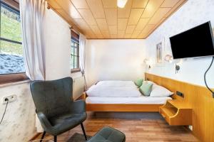 a small bedroom with a bed and a chair at Gästehaus Absbachtal in Bad Rippoldsau-Schapbach