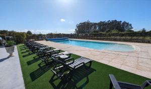 a row of chairs sitting next to a swimming pool at Villa com 4 apartamentos in Apúlia