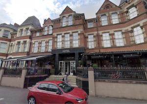 a red car parked in front of a building at Queens Hotel Belfast in Belfast