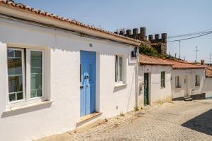 a row of houses with a blue door on a street at Casa Do Castelo in Beja