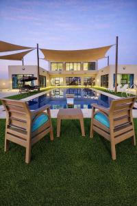 two chairs and a table in front of a swimming pool at Devon Chalet in Amman