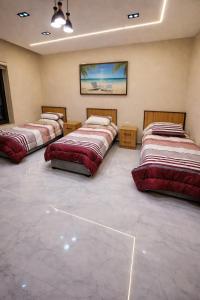 three beds are lined up in a room at Devon Chalet in Amman