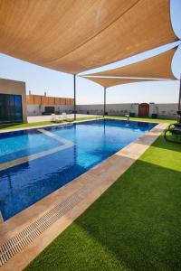 an outdoor swimming pool with a large umbrella over it at Devon Chalet in Amman +3 photos