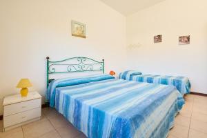 a bedroom with two beds with blue and white sheets at Mare Etrusco Villetta D2 in Populonia