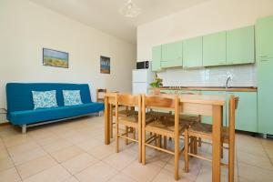 a kitchen with a table and chairs and a blue couch at Mare Etrusco Villetta D2 in Populonia