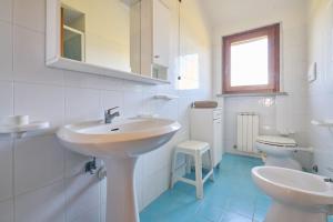 a white bathroom with two sinks and a toilet at Mare Etrusco Villetta D2 in Populonia +16 photos