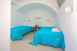two beds in a room with blue sheets at Kaladi Rock Avlemonas in Avlemonas