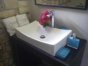 a bathroom sink with a vase of flowers on it at Kaladi Rock Avlemonas in Avlemonas +19 photos