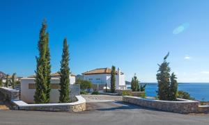 a house with trees in front of the ocean at Kaladi Rock Avlemonas in Avlemonas