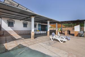 a patio with white chairs and a building at Finca El Abuelo in Lepe