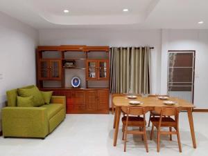 a living room with a table and a green couch at บ้านกรรณิการ์ in Chiang Mai
