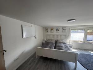 a white bedroom with a bed in a room at M und S - Landidyll am Weiher in Harsum