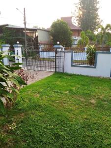 a fence with a gate in a yard with grass at บ้านกรรณิการ์ in Chiang Mai