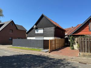 a black house with a fence and some houses at M und S - Landidyll am Weiher in Harsum