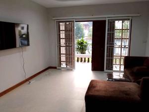 a living room with a couch and two large windows at บ้านกรรณิการ์ in Chiang Mai