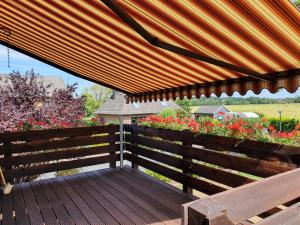 a wooden bench with a large umbrella on a deck at Ferienwohnung in Etelsen in Langwedel
