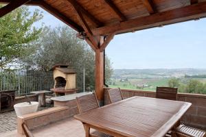 a wooden table and chairs on a patio with a grill at Tenuta Paradiso in Portacomaro