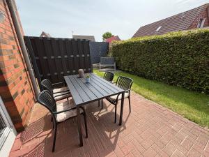 a wooden table and chairs on a brick patio at Ferienwohnung Charly in Carolinensiel