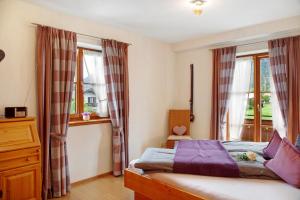 a bedroom with a bed and two windows at Landhaus Bergkulisse in Wallgau