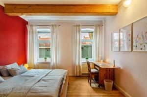 a bedroom with a bed and a desk and two windows at Gulfhof Oldersum Erdgeschoss in Moormerland