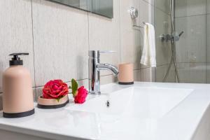 a bathroom sink with a soap dispenser and a pink rose at Oásis Fonte Grande in Ponta Delgada +34 photos