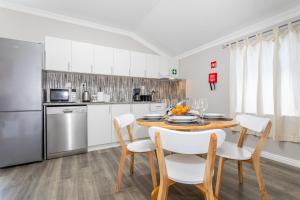 a kitchen with a table and chairs and a refrigerator at Oásis Fonte Grande in Ponta Delgada