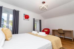 a bedroom with a white bed and a red chair at Oásis Fonte Grande in Ponta Delgada