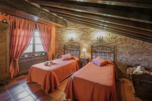 a bedroom with two beds and a brick wall at Casa Rural Los Beatos in Urueña
