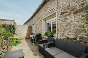 an outdoor patio with furniture and a brick wall at Gite Les Dauphins à Matignon in Matignon