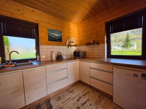a kitchen with wooden cabinets and a sink and two windows at Domki przy Młynie " Koło Młyńskie " in Krościenko +26 photos