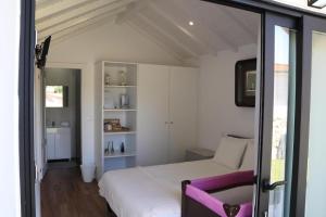 a bedroom with a white bed and a purple chair at Casa do Mestre Inteira in Vila de Punhe