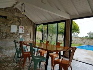 a dining room with a table and chairs and a pool at Casa do Mestre Inteira in Vila de Punhe