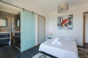 a bedroom with a white bed and a bathroom at Villa Kalliste in Olmeto