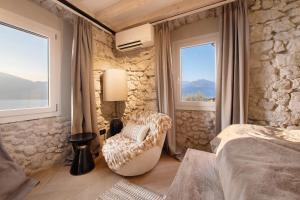 a bedroom with a bed and a chair and windows at Cozy Sommavilla Residence in Brenzone sul Garda