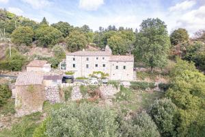 an old stone house on a hill with trees at La Casita in Beauvène