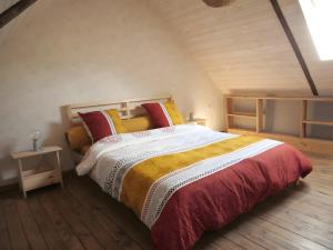a bedroom with a large bed with red and yellow pillows at Gîte Le Penn-ty in Rosporden