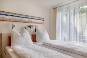 two beds with white pillows sitting next to a window at Ferienwohnung am Neumagen in Staufen im Breisgau