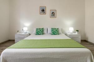 a white bedroom with a large bed with a green blanket at Casa Belvedere in Codrongianos