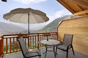 a table and chairs on a balcony with an umbrella at Unterötzbauerhof - Fewo Rosenblick in Tirolo
