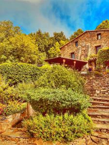 an old stone building with some bushes and stairs at Le Grand Mas de Can Noy in Montferrer