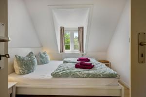 a bed with two red pillows on it in a room at Fewo Silbermöwe in Pellworm