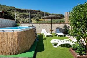 a backyard with a pool and chairs and an umbrella at La Breña in Barbate