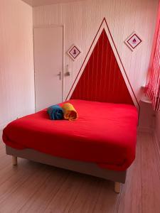 a dog laying on a red bed in a room at La Voile Blanche - 36 in Pornic