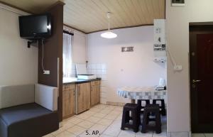 a kitchen with a table and a tv in it at CSABA-EMILKA-SPA Apartmanok in Hajdúszoboszló