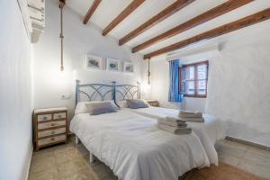 two beds in a bedroom with white walls and wooden beams at Casa La Roca in Pollença +20 photos