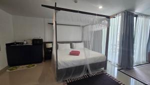 a bedroom with a canopy bed with a red box on it at joyful theKris 205 in Ban Lum Fuang
