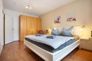 a bedroom with a large white bed with blue pillows at Wohnung C1 - Haus A Cappella in Binz +21 photos